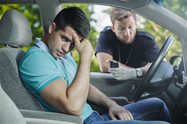 A young man pulled over for drunk driving looks away from the officer in shame