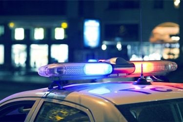 Close up of a police car with its lights on driving through a city at night