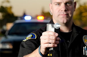 A police officer holds up a breathalyzer to test someone for driving under the influence