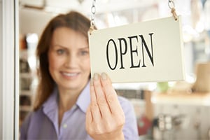 Business law concept, a woman business owner flips the sign on the shop door to show it is now open.